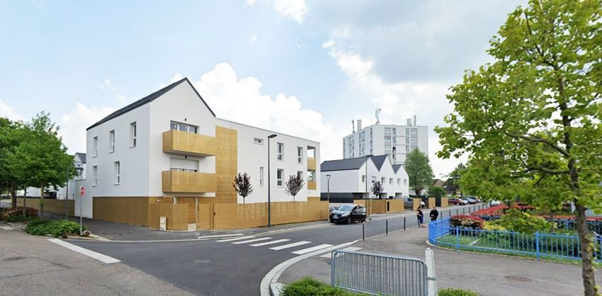 Petit immeuble blanc à balcons en bois, au carrefour d’une rue pavillonnaire